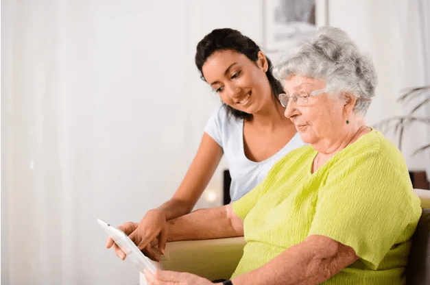 A woman and an older person looking at something on a tablet.
